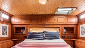 Une cabane avec un lit, des armoires en bois et une lucarne.