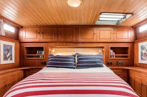 A cabin with a bed, wooden cabinets, and a skylight.