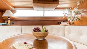 Un coin repas avec une table en bois, un saladier de fruits et une planche à fromages.
