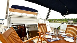Une table à manger avec des chaises, une bouteille de champagne et des assiettes, le tout sur un bateau.