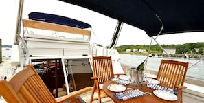 Una mesa con sillas, una botella de champán y platos en un barco.