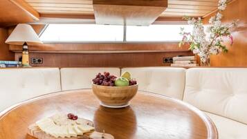 A dining area with a wooden table, a bowl of fruit, and a cheese board.