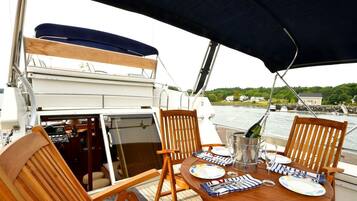 Une table à manger avec des chaises, une bouteille de champagne et des assiettes, le tout sur un bateau.