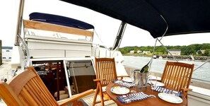 A dining table with chairs, a bottle of champagne, and plates on a boat.