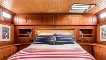 A cabin with a bed, wooden cabinets, and a skylight.