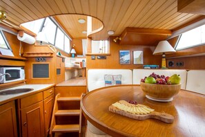 Una cocina compacta con armarios de madera, microondas, lavabo y zona de comedor con una mesa dispuesta para una comida.