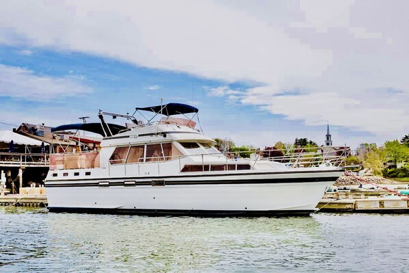 A large white yacht docked at a marina with a clear sky and a church in the background.