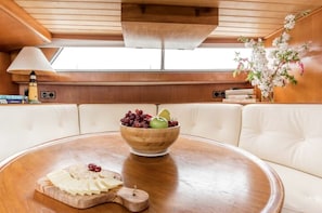 Un comedor con una mesa de madera, un cuenco de fruta y una tabla de quesos.