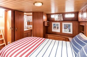 A cabin with a bed, wooden walls, a small kitchenette, and a window with curtains.