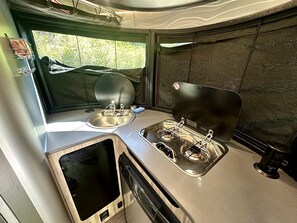 Une cuisine de taille réduite, équipée d’un évier, d’une cuisinière et d’une fenêtre.