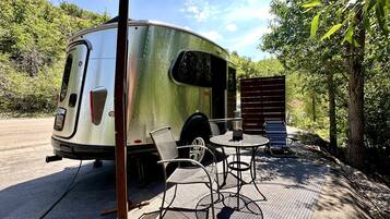 A trailer with a covered patio area, including a table and chairs.