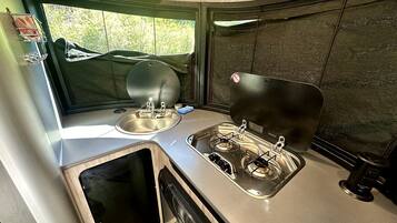 A compact kitchen with a sink, stove, and window.