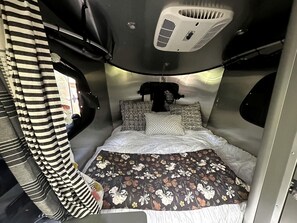 A compact, well-lit interior with a bed, pillows, and a headboard. - Original and Charming Airstream Rental in Salt Lake City for Glamping in Utah (Salt Lake City)