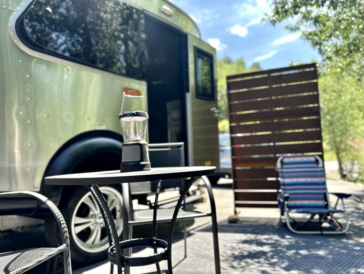 A table with a blender, a chair, and a parked camper.