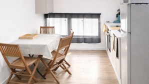 Een moderne keuken met een eethoek, witte kastjes en uitzicht door een raam.