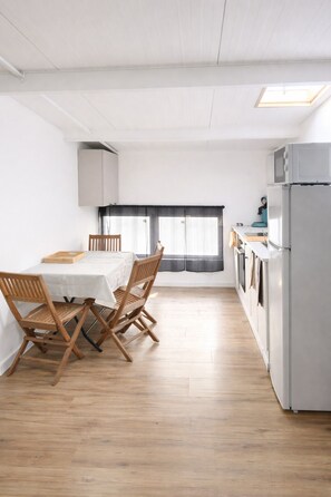 Eine moderne Küche mit Essbereich, weißen Schränken und Blick durch ein Fenster.