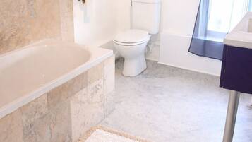 Une salle de bain équipée d’une baignoire, de toilettes et d’un espace douche.