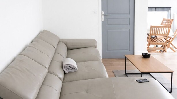 Een moderne woonkamer met een beige hoekbank, een houten salontafel en een grijze deur.