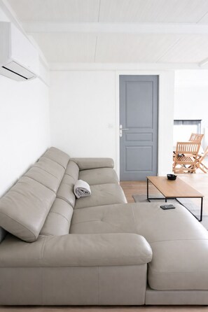 Een moderne woonkamer met een beige hoekbank, een houten salontafel en een grijze deur.
