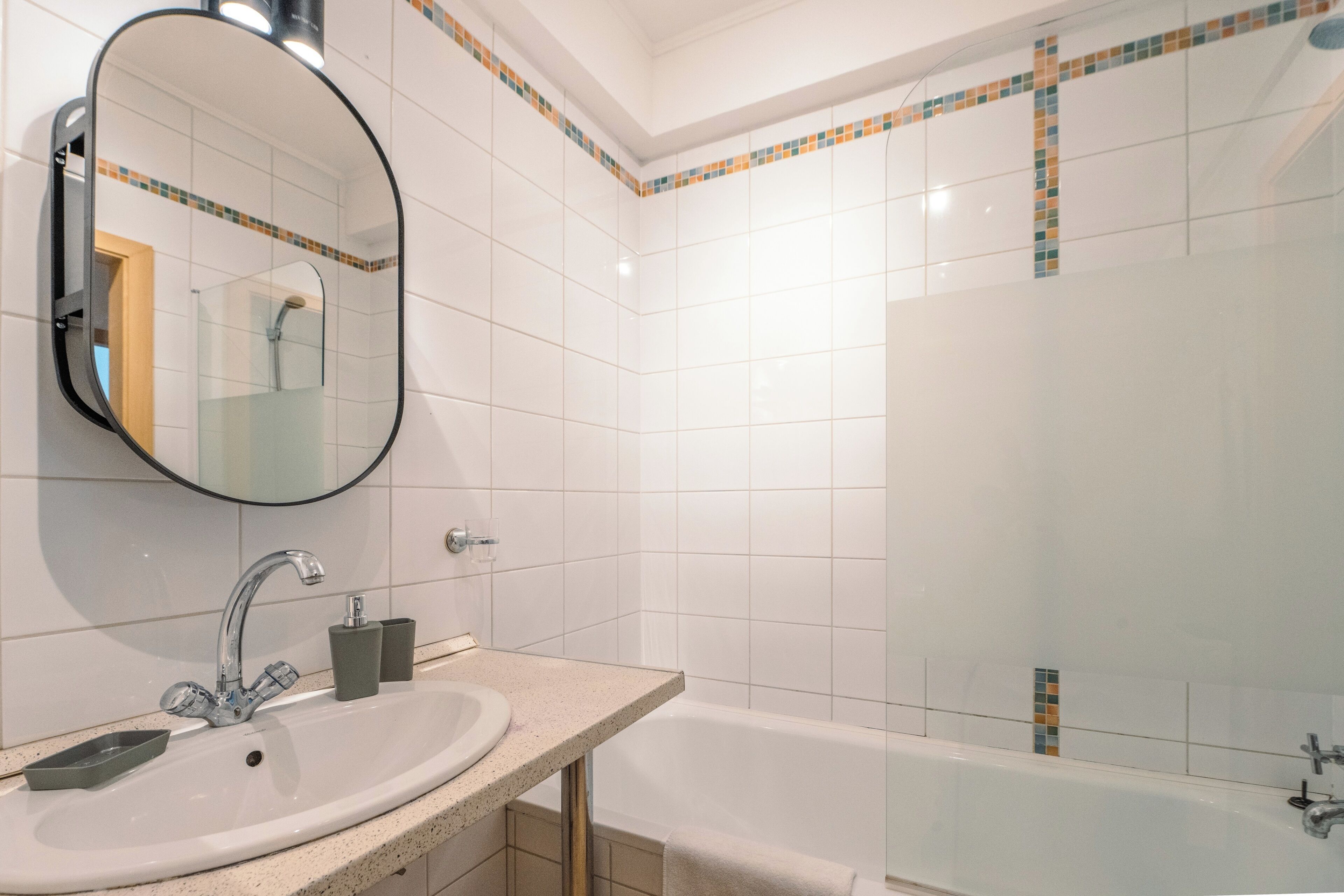 Un baño con lavabo, espejo y bañera.