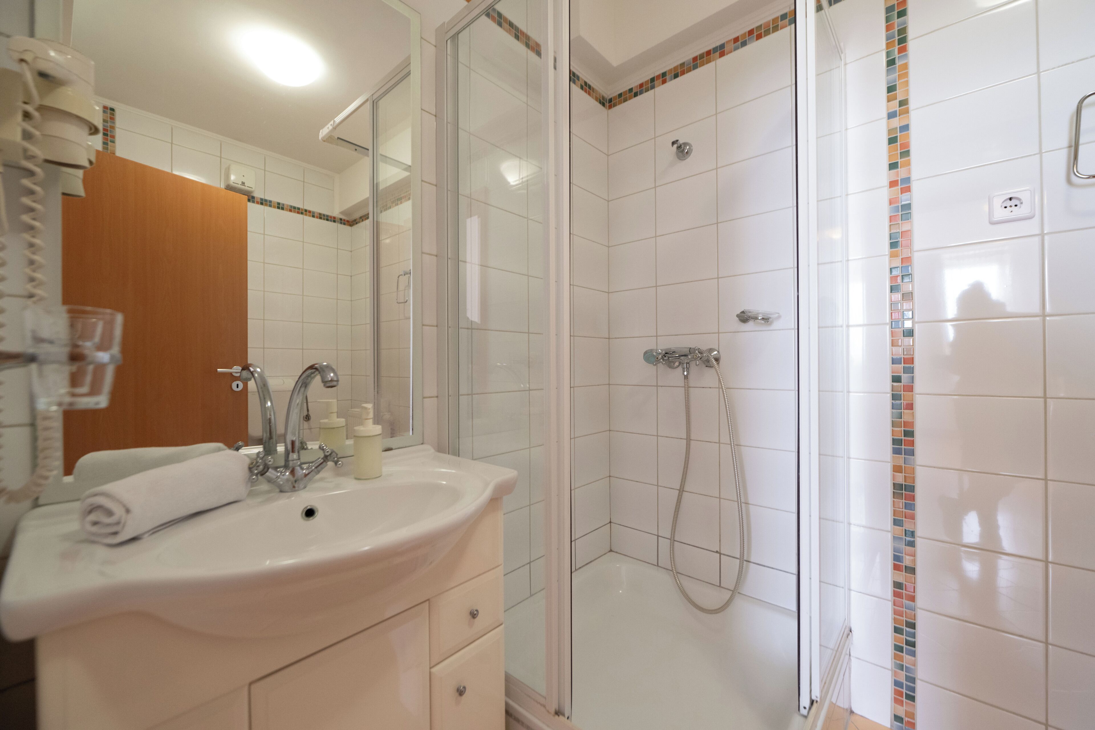 A bathroom with a sink, mirror, and shower.