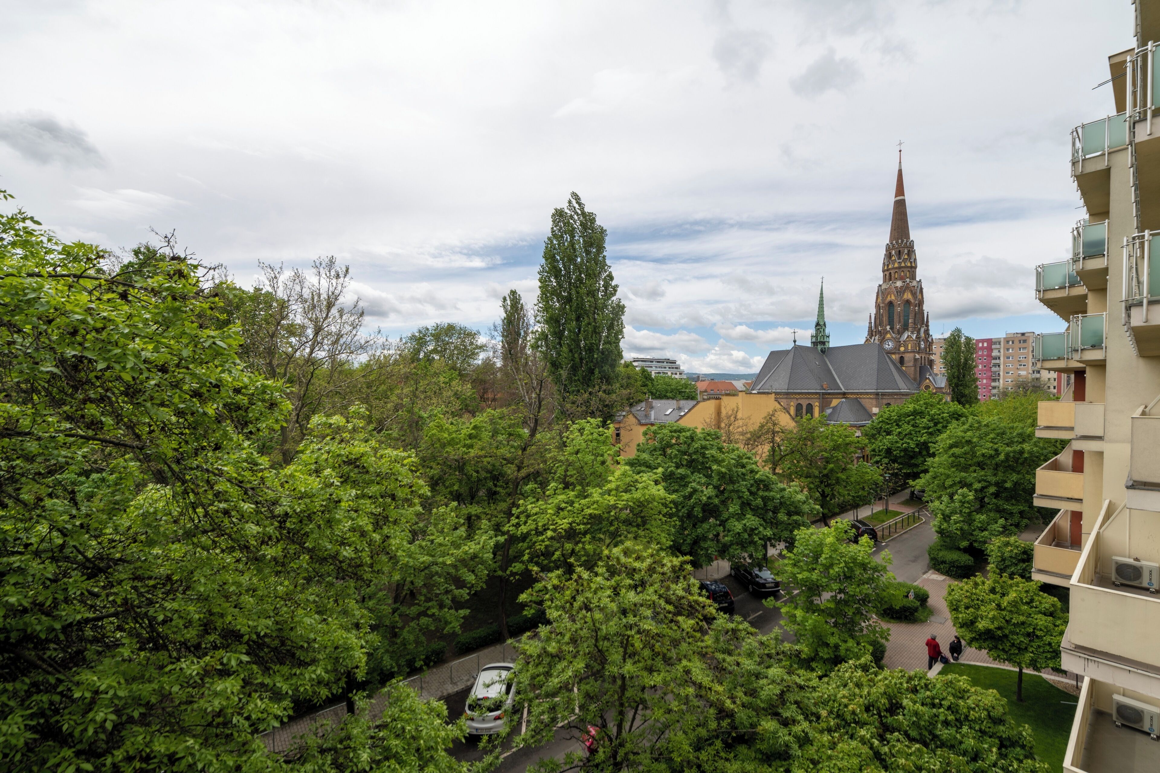 Ein Wohngebiet mit einem Kirchturm, üppiger Vegetation und einer Straße.