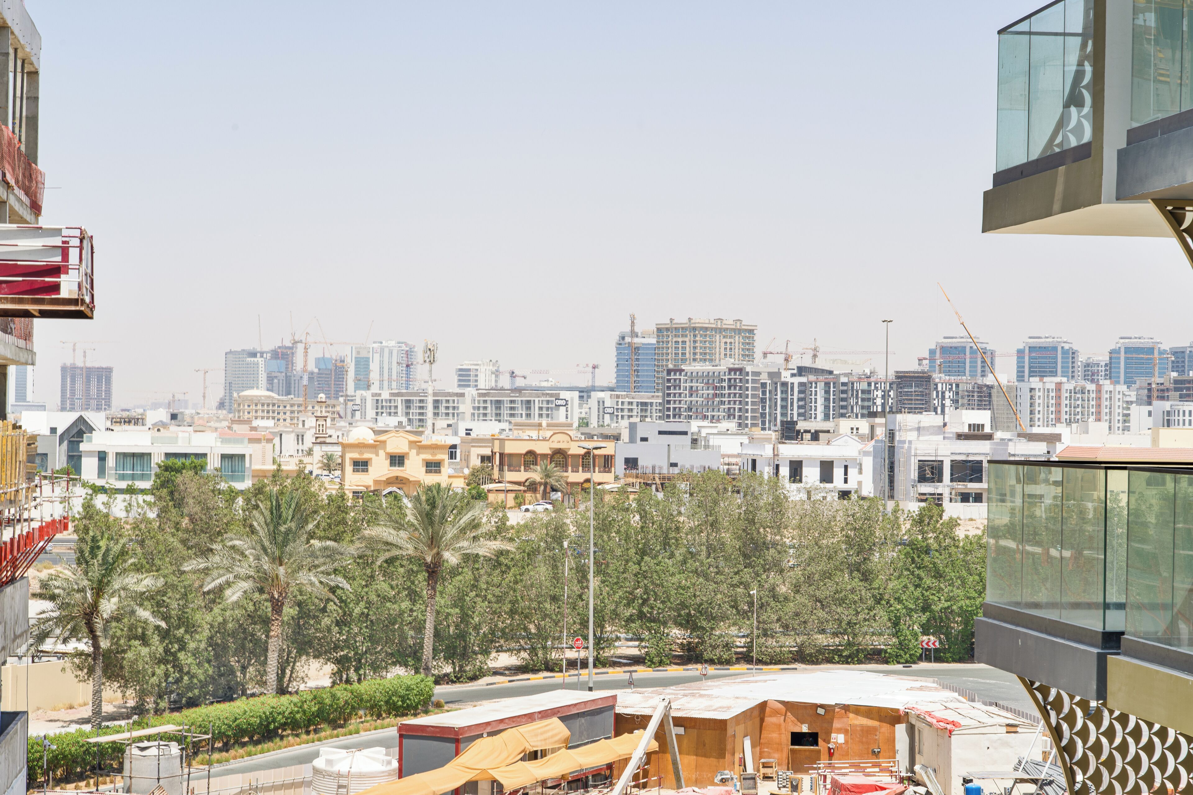 Un paysage urbain avec des bâtiments modernes, des palmiers et un chantier de construction.