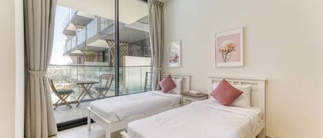 A bedroom with two beds, a balcony with a table and chairs, and a large window.