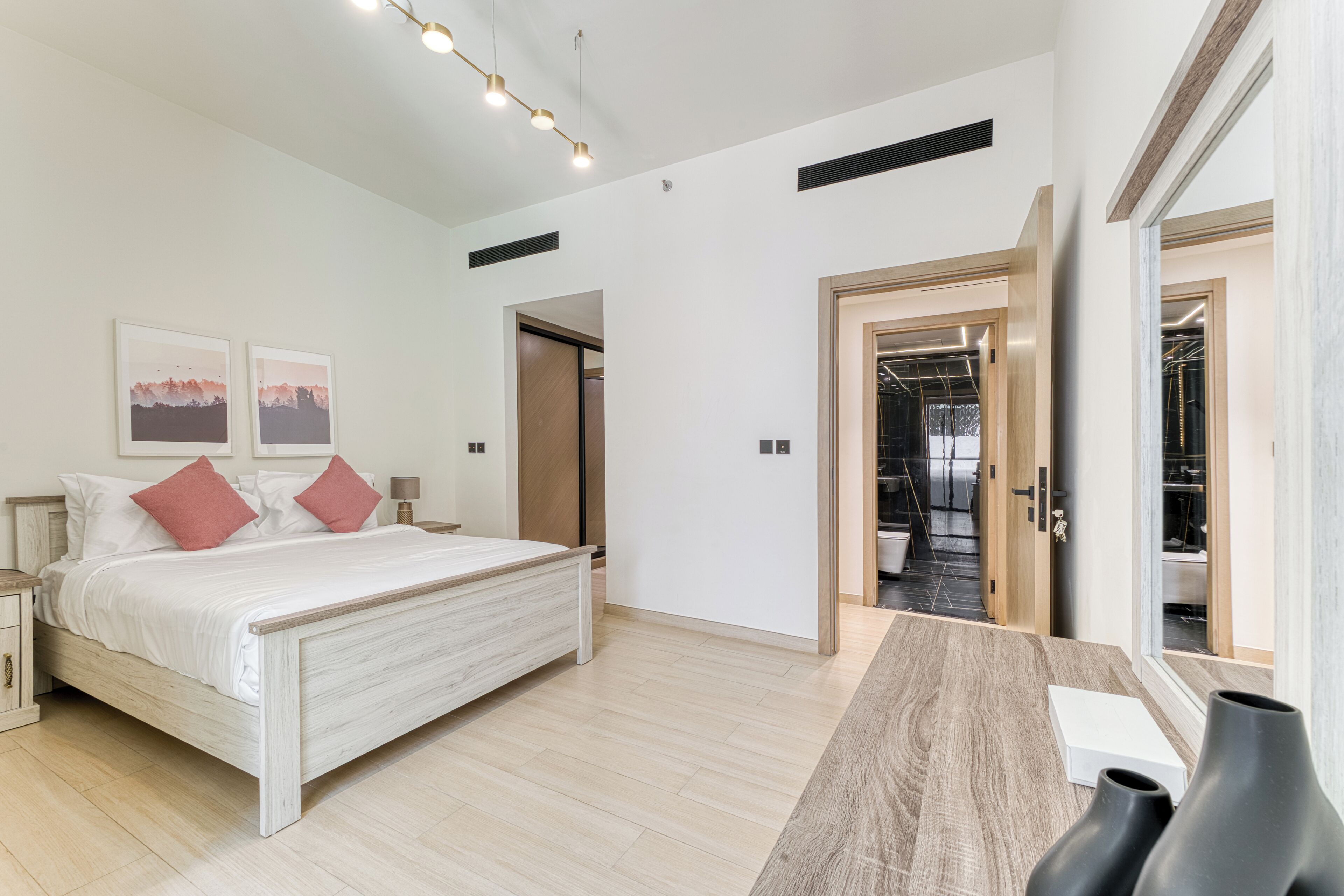 Ein modernes Schlafzimmer mit Bett, Nachttischen, Schreibtisch und Spiegel.
