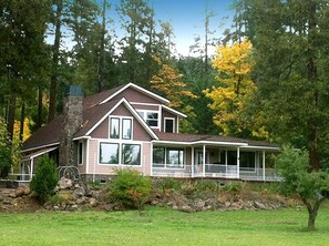 A two-story house with a stone chimney, large windows, and a covered porch. - Luxury Cabin Rental in the Cascade Mountains near Crater Lake, Southern Oregon (Prospect)