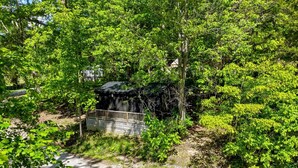 A gravel path leading to a wooden bridge over a small water feature, surrounded by dense green foliage. - Nature-Forward Glamping Resort with Forest Paths and Meadow Hangouts in Stanton, Kentucky (Stanton)
