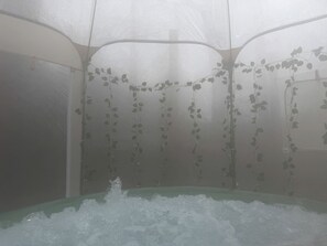 Ein Zimmer mit einer mit Wasser gefüllten Badewanne, umgeben von blattverzierten Wänden.