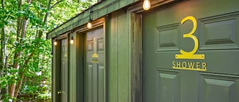 A green building with three doors labeled 'SHOWER' and the number '3' on the right door.