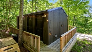 A small cabin with a deck, a covered porch, and a single door. - Nature-Forward Glamping Resort with Forest Paths and Meadow Hangouts in Stanton, Kentucky (Stanton)