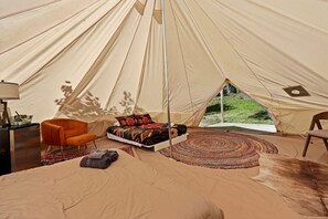 Ein Zelt mit Bett, Stuhl, kleinem Tisch und Blick ins Freie.