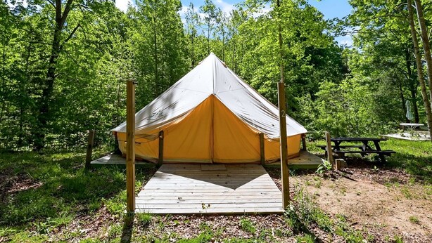 A single-occupancy tent with a wooden deck in a forested area. - Nature-Forward Glamping Resort with Forest Paths and Meadow Hangouts in Stanton, Kentucky (Stanton)