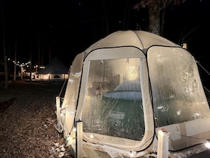 Una carpa con el logo de Coleman, rodeada de árboles y un suelo cubierto de hojas.
