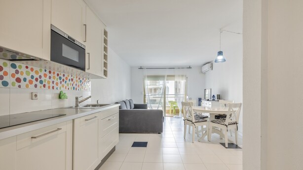 Una cocina moderna con armarios blancos, un microondas y un salpicadero colorido.