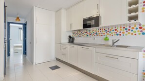 Una cocina moderna con armarios blancos, un lavamanos de acero inoxidable y un salpicadero de pared con lunares de colores.