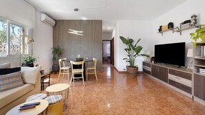 A modern living room with a sofa, dining table, chairs, a TV, and a large window. - Casa Fleming with Private Pool, Wi-Fi, and Air Conditioning in Miami Platja (Miami Platja)