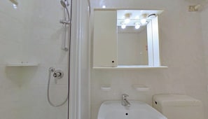 Ein Badezimmer mit Dusche, Waschbecken, Toilette und einem Spiegel über dem Waschbecken.