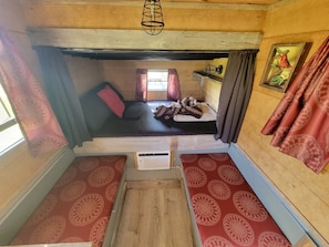A small, cozy room with a bunk bed, a wooden ladder, and a small table.