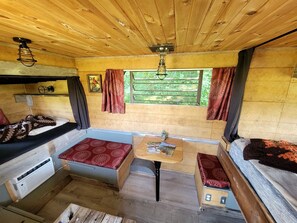 A compact RV interior with a kitchenette, seating area, and a table with a magazine.