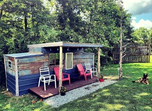 A small wooden structure with a porch, two white chairs, and two red chairs. - Cozy Tiny House on Working Farm, for Fun Glamping Trips in Kentucky (Owenton)