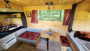A compact RV interior with a kitchenette, seating area, and a table with a magazine. - Cozy Tiny House on Working Farm, for Fun Glamping Trips in Kentucky (Owenton)