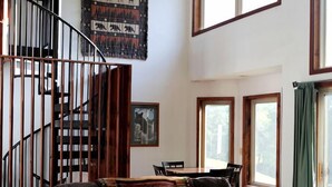 A living room with a sofa, a coffee table, a staircase, and a large window.