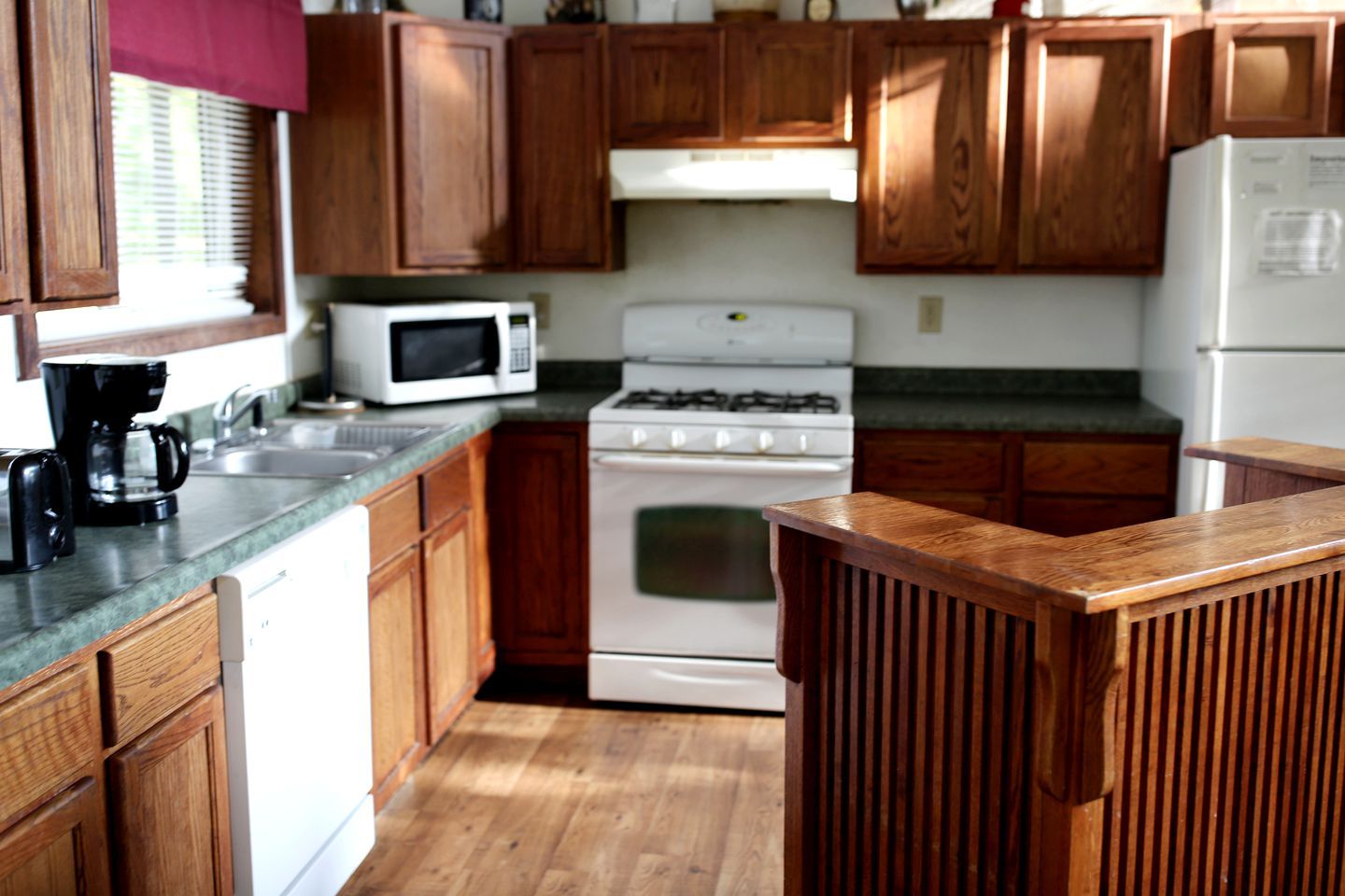 A kitchen with wooden cabinets, a microwave, a stove, and a refrigerator.