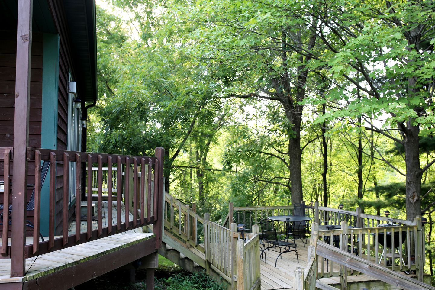 A wooden deck with a table and chairs, surrounded by trees.