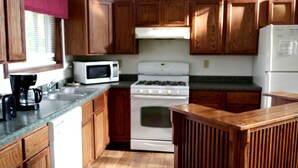 A kitchen with wooden cabinets, a microwave, a stove, and a refrigerator.