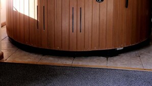 A hot tub in a room with a window, a door, and a thermostat on the wall.
